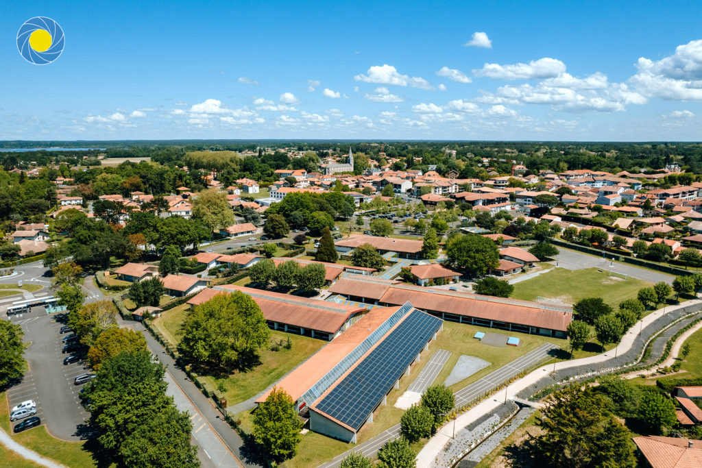 Collège de la ville de Soustons dans les Landes vu d'un drone et son église avec des panneaux solaires et un parking pour voitures