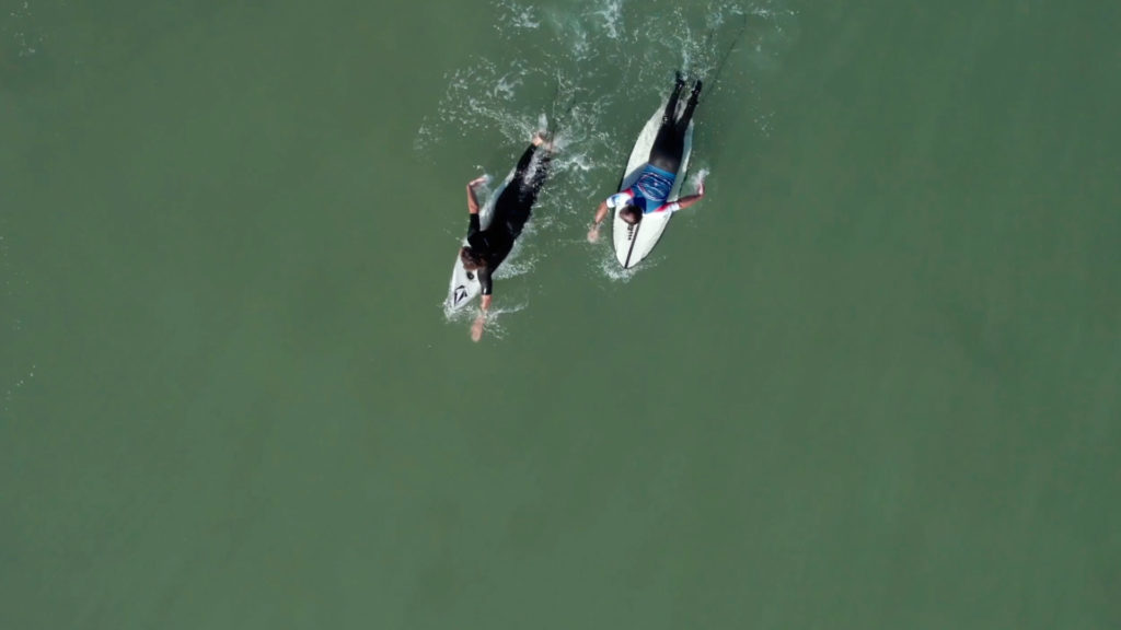 Deux surfeurs handi surf vus d'un drone qui rament sur leur planche dans l'océan atlantique