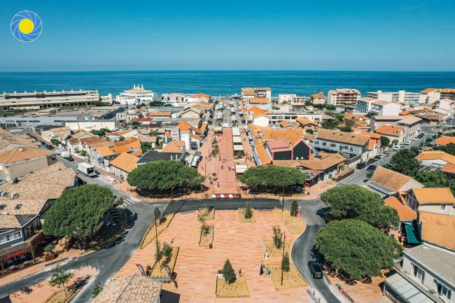 Une place pavée et paysagée vue d'un drone avec une allée qui mène à une plage de Lacanau